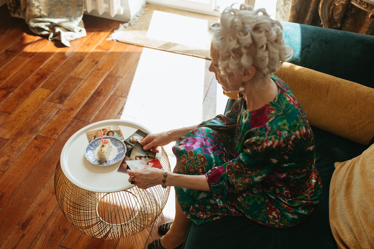 Senior woman with curlers reminiscing over old photographs in a cozy living room.